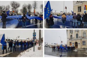 FOTO-VIDEO: Steagul uriaş al UE, adus de români din Diaspora, a ajuns la Alba Iulia. Jurnalistul Mălin Bot, printre protestatarii din faţa Prefecturii Alba