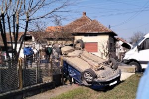 FOTO. Maşină răsturnată în Odoreu, după un impact cu o dubă. Autoturismul a ajuns peste gardul unei case