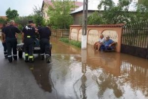 O fotografie cu doi săteni care stau pe bancă în timp ce pompierii scot apa, devenită virală pe internet