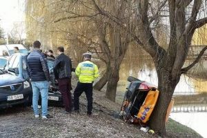 FOTO Taxi cu roţile în sus pe malul Cibinului – Stă să cadă în râu